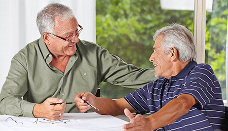 Photo of two elderly man talking of some paperwork and smiling